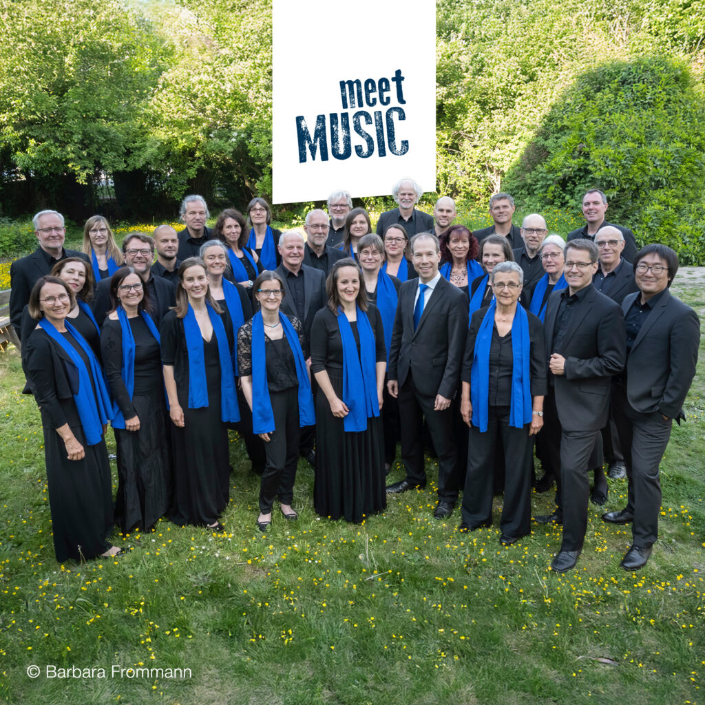 Bonner Kammerchor in schwarzer Konzertkleidung mit blauen Schals im Grünen für Power of Nature bei meetMUSIC