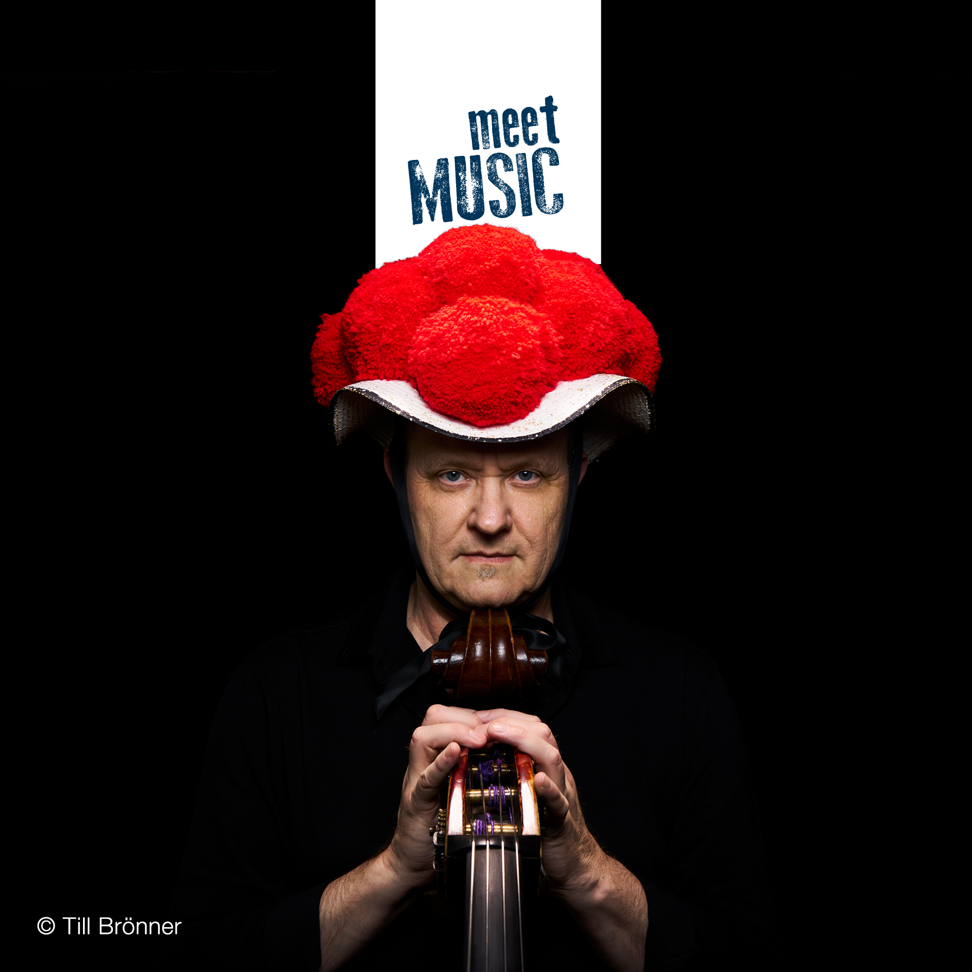 Dieter Ilg mit Kontrabass vor schwarzem Hintergrund und auffälliger roter Kopfbedeckung bei meetMUSIC