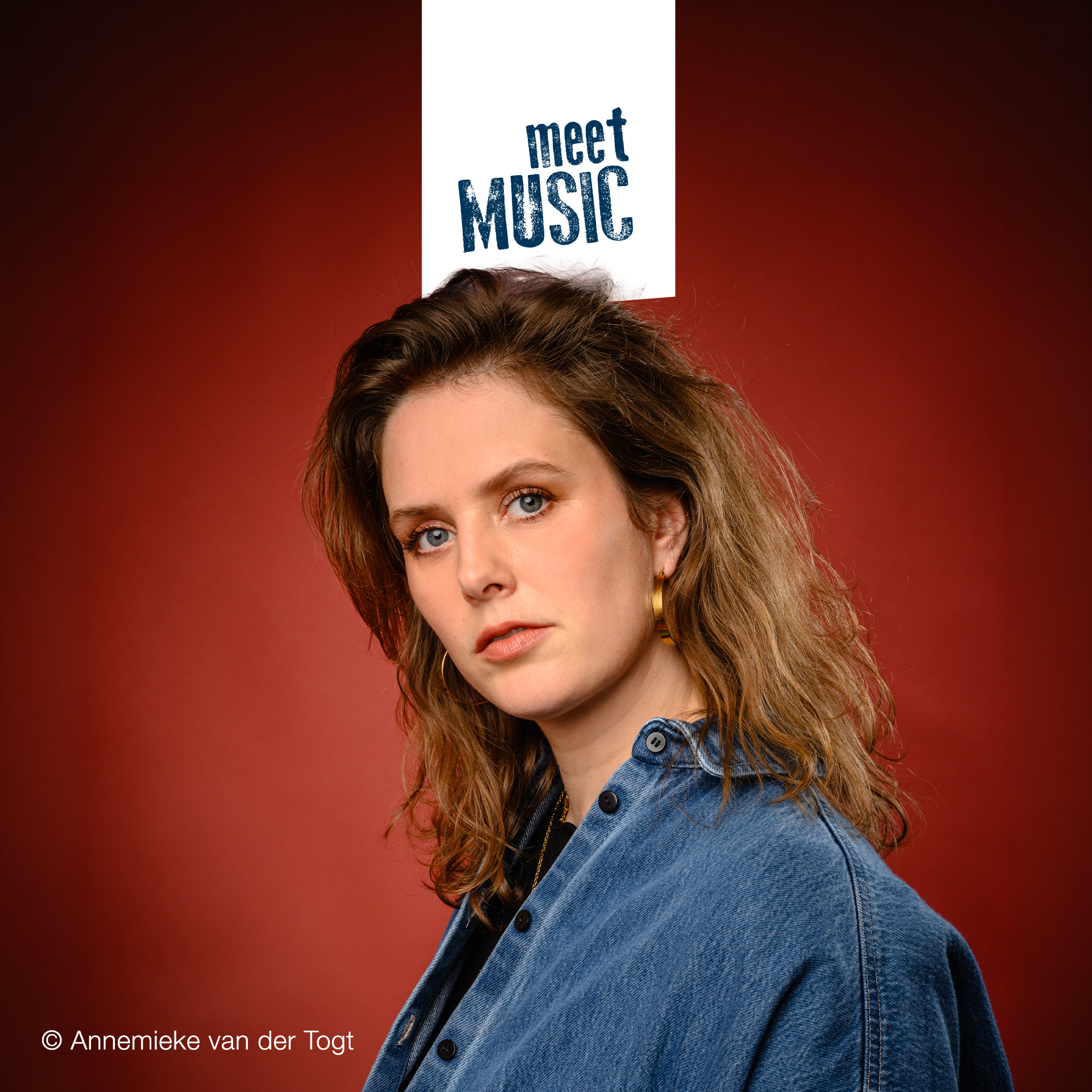 Maaike Ouboter in einem Jeanshemd posiert vor einem roten Hintergrund, über ihr steht „meet MUSIC“.
